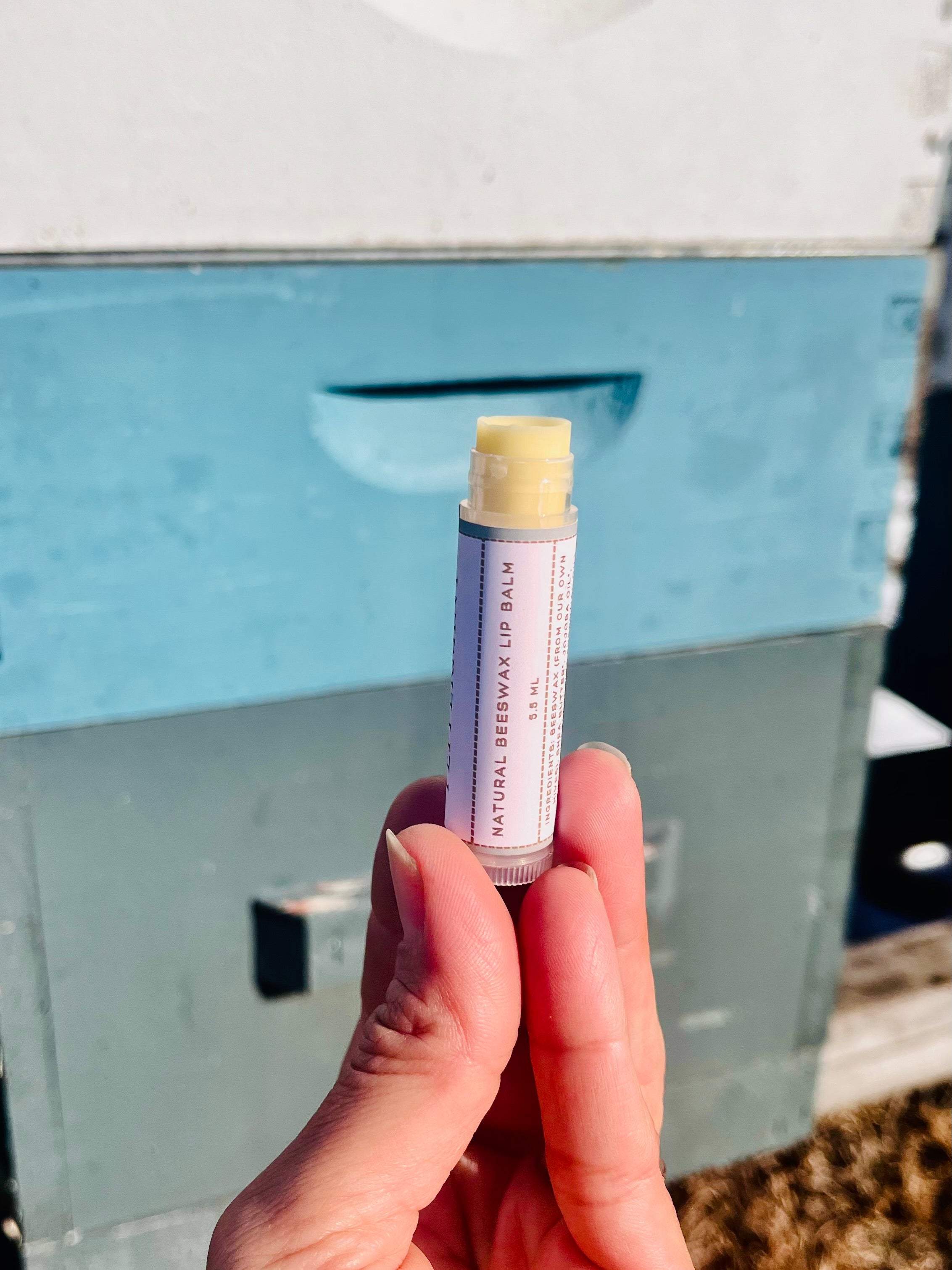 Hand holding a lip balm stick with a blue background
